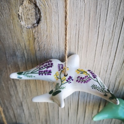 Pássaro decorativo em cerâmica branca com pintura floral pendurado por corda