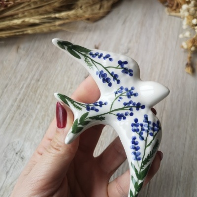 Estatueta cerâmica de pássaro com flores azuis e folhas verdes