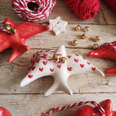 Enfeites de estrela do mar vermelhos e brancos com fios e guizos sobre madeira clara