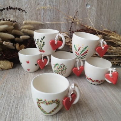 Seis chávenas de cerâmica branca decoradas com padrões florais e corações vermelhos pendurados nas pegas