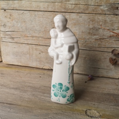 Estátua branca em cerâmica com padrão floral verde sobre madeira rústica