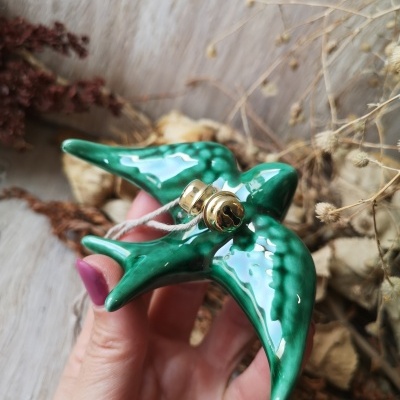 Figura decorativa em cerâmica verde em forma de pássaro com sinos dourados