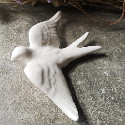 Figura decorativa de pássaro em cerâmica branca com textura suave
