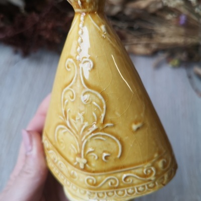 Objeto de cerâmica amarelo com relevo floral e geométrico em forma de cone