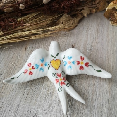 Pássaro decorativo em cerâmica branca com pintura floral colorida e coração amarelo