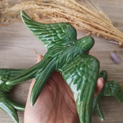 Figura decorativa de pássaro verde em cerâmica vidrada com relevo e asas abertas
