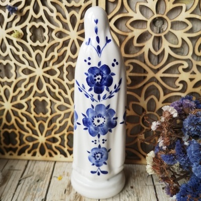 Estatueta em cerâmica com flores azuis, fundo decorativo em madeira e flores secas.