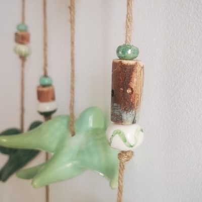 Detalhe de móvel decorativo com pássaros e contas em cerâmica pendurados em cordas