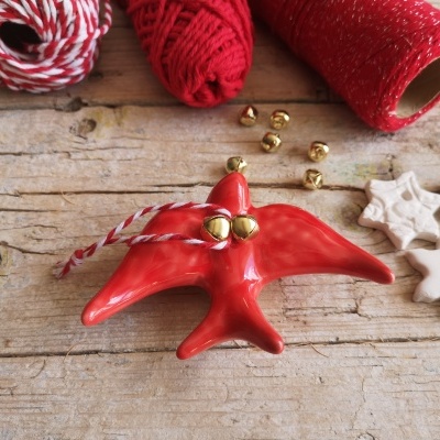 Decoração de estrela vermelha com sinetas e rolos de linha vermelhos sobre mesa de madeira