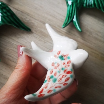 Pássaro decorativo em cerâmica com padrão de folhas coloridas