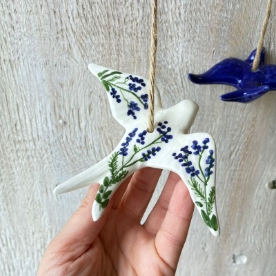 Pássaros decorativos de cerâmica pendurados com corda em fundo de madeira