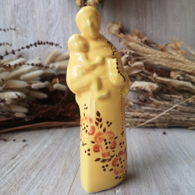 Estatueta cerâmica amarela de figura religiosa com criança e flores decorativas