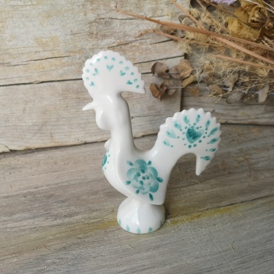 Estatueta de galo de cerâmica branca com padrões florais e corações azuis e verdes.