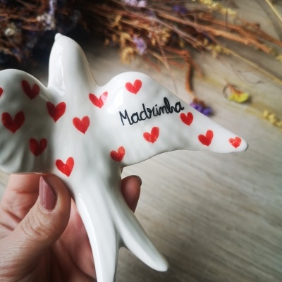 Figura de pássaro em cerâmica branca com corações vermelhos e texto 'Madrinha'
