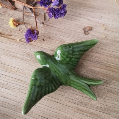 Peça decorativa cerâmica verde em forma de pássaro com flores secas