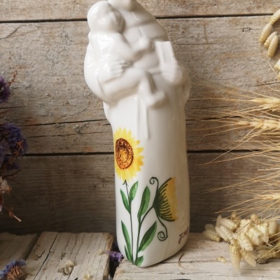 Estátua cerâmica branca com pintura de girassol sobre madeira rústica e flores secas