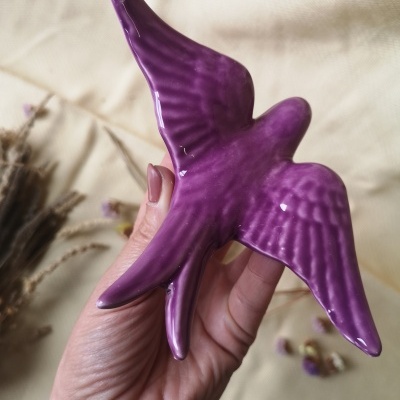 Figura decorativa em cerâmica roxa em forma de pássaro com textura nas asas