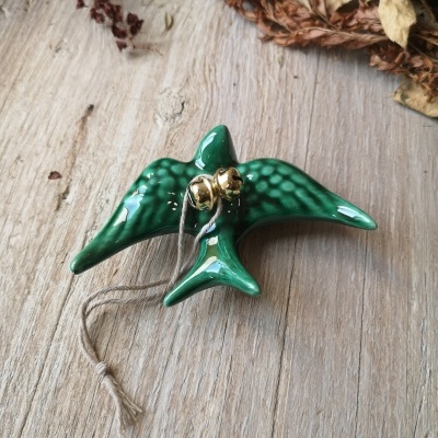 Peça decorativa em cerâmica verde em forma de pássaro com dois sinos dourados e cordão rústico