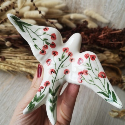 Pássaro decorativo em cerâmica branca com flores vermelhas e folhas verdes