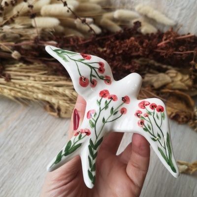 Escultura de pássaro em cerâmica decorada com flores vermelhas e verdes