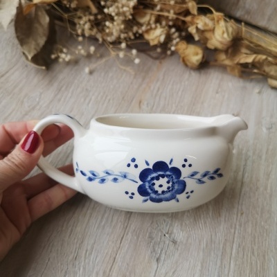Leiteira de porcelana branca com flores azuis e fundo de madeira clara