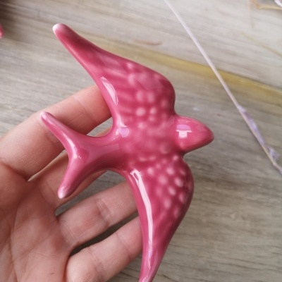 Pássaro decorativo rosa em cerâmica com pontos brancos na mão