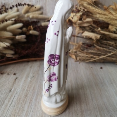 Estátua religiosa cerâmica branca com flores roxas e base creme