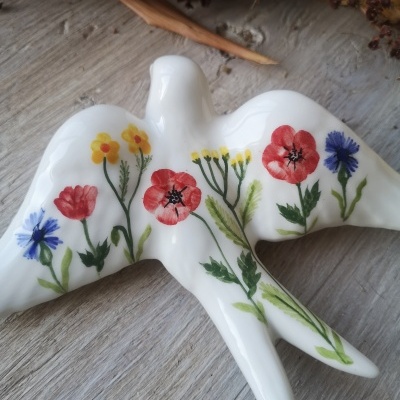 Figurinha de pássaro branco em cerâmica com flores pintadas coloridas