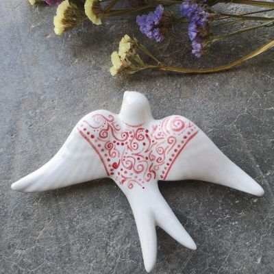 Estatueta de cerâmica branca em forma de ave com padrão vermelho
