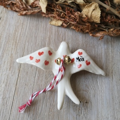 Pássaro decorativo branco com corações vermelhos, palavra 'Mãe', sinos e cordão