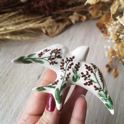 Peça decorativa em cerâmica branca em forma de pássaro com pintura floral