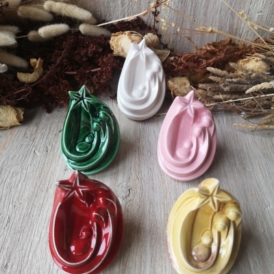 Mini presépios cerâmicos coloridos com estrela em cima sobre madeira e flores secas