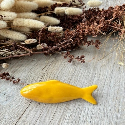 Peixe decorativo amarelo em cerâmica com flores secas ao fundo
