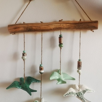 Móvel decorativo com pássaros de cerâmica pendurados em madeira rústica