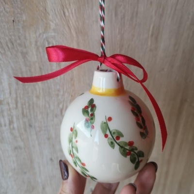Bola de Natal branca com desenhos de folhas e bagas, laço vermelho e cordão para pendurar