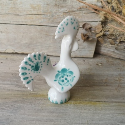 Figura cerâmica branca em forma de galo com padrões verdes