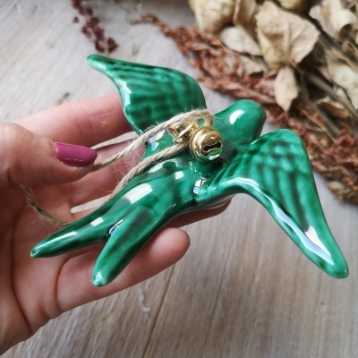 Ornamento de cerâmica verde em forma de pássaro com sinos dourados e corda rústica