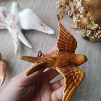 Pássaro de cerâmica castanho esmaltado com fundo de madeira e flores secas