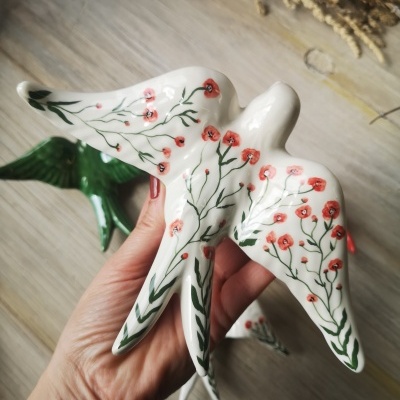 Figura decorativa de pássaro branco com flores vermelhas e folhas verdes