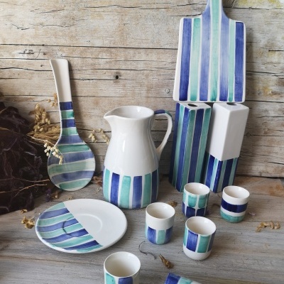 Conjunto de loiça em cerâmica com padrão listrado azul e verde sobre fundo rústico de madeira