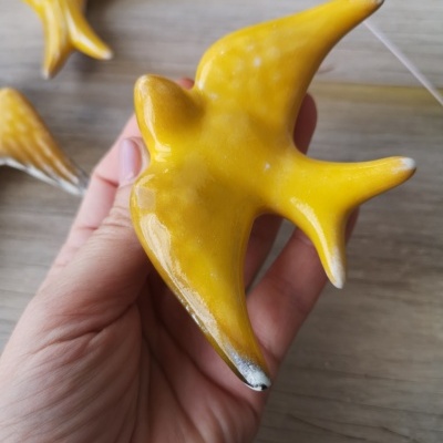 Figurinha amarela de pássaro com textura brilhante segurada na mão