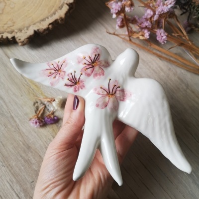 Estatueta de cerâmica branca em forma de pássaro com flores cor de rosa