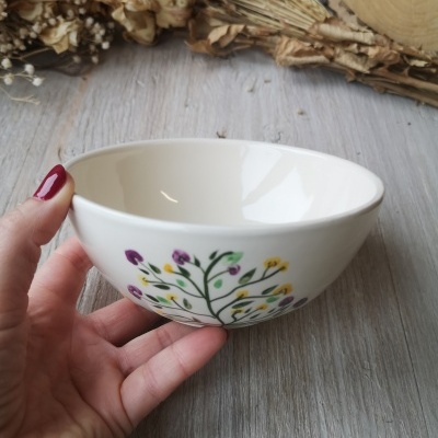 Taça branca decorada com flores coloridas segurada por mão