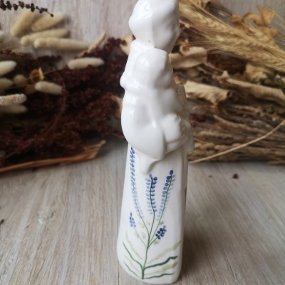 Figura decorativa em porcelana branca de mulher com criança e flores pintadas.