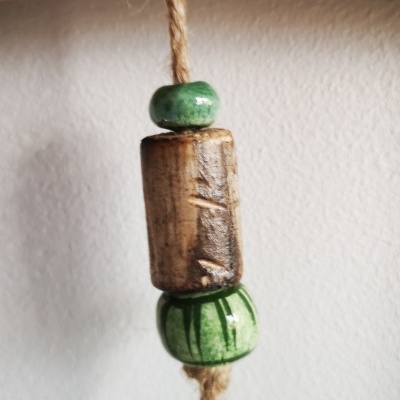 Pendente decorativo com contas verdes e castanhas pendurado em cordel