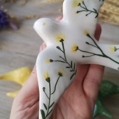 Escultura de pardal em cerâmica com flores amarelas e verdes