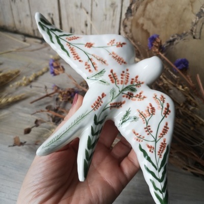 Figura decorativa de pássaro em cerâmica pintada com flores e folhas