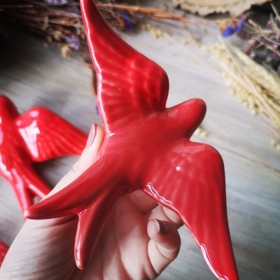 Estatueta vermelha brilhante em forma de pássaro com asas abertas