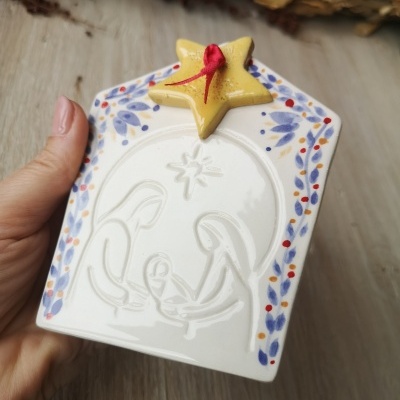 Peça decorativa de cerâmica branca com relevo da Sagrada Família e estrelas coloridas