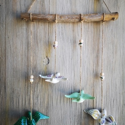 Móvel pendurado com pássaros de cerâmica coloridos em madeira rústica